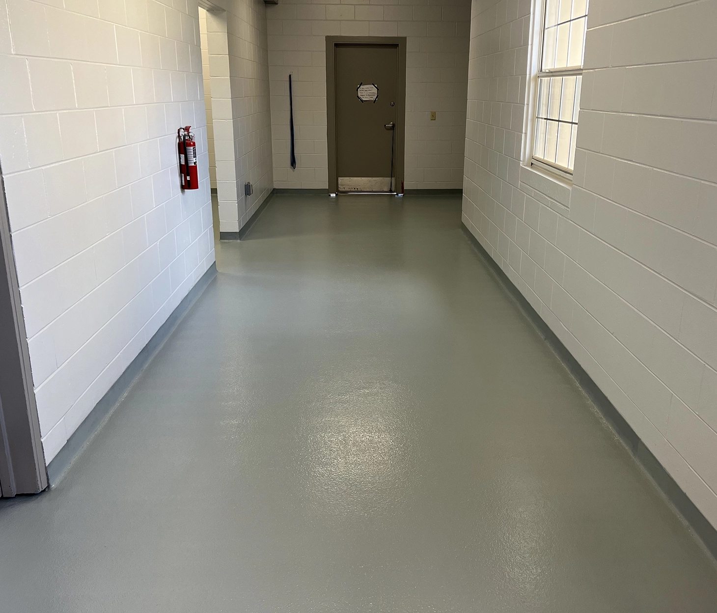 Smooth gray epoxy floor coating in a clean, sanitary hallway at an animal services facility, featuring cove base and block walls for easy maintenance.