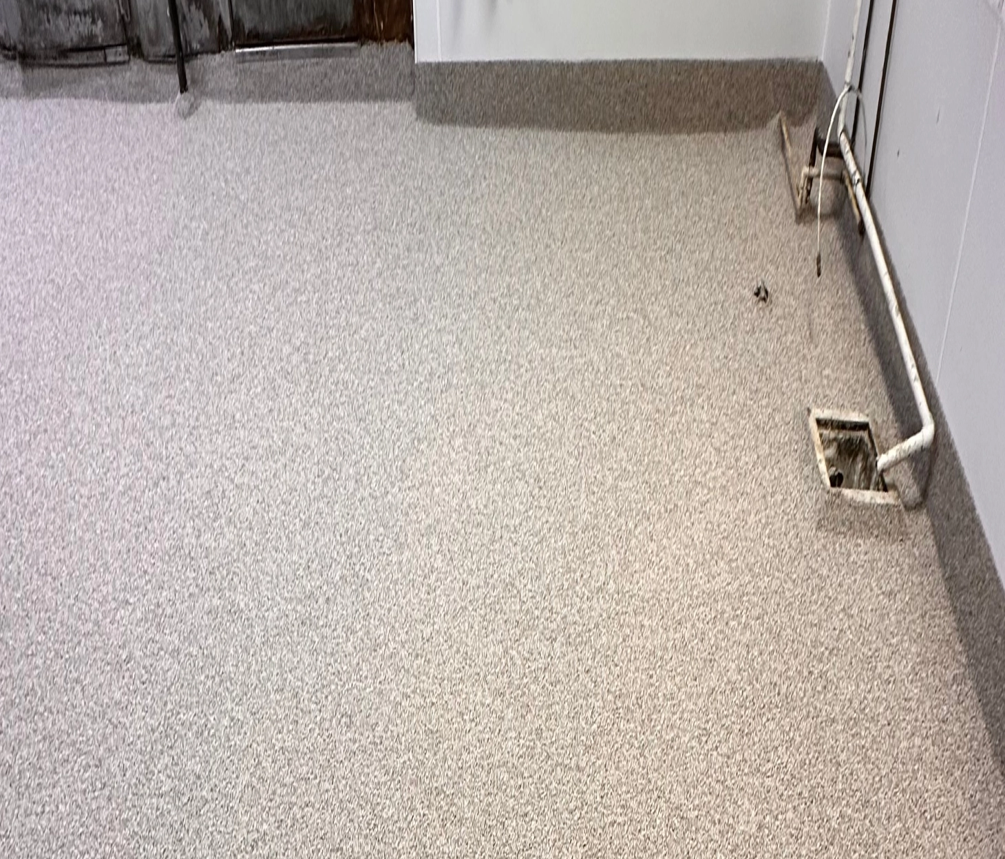 Light-colored urethane cement flooring with integral cove base and exposed utility piping in a food prep area
