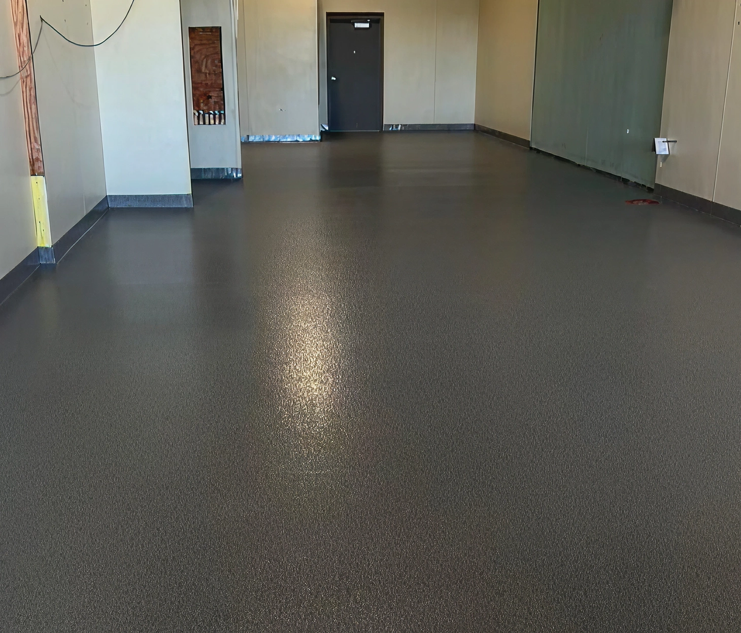 Commercial kitchen space featuring a dark, slip-resistant epoxy floor system with seamless cove base for durability and hygiene.