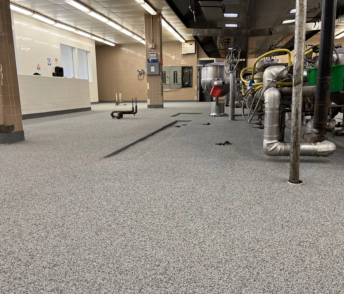 Wide-angle view of industrial epoxy flake floor at Spelman College, featuring textured finish, integrated drains, and commercial kitchen equipment.